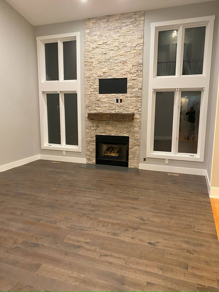 Whole-house renovation featuring two-story living room with stacked-stone fireplace and reclaimed-wood mantel