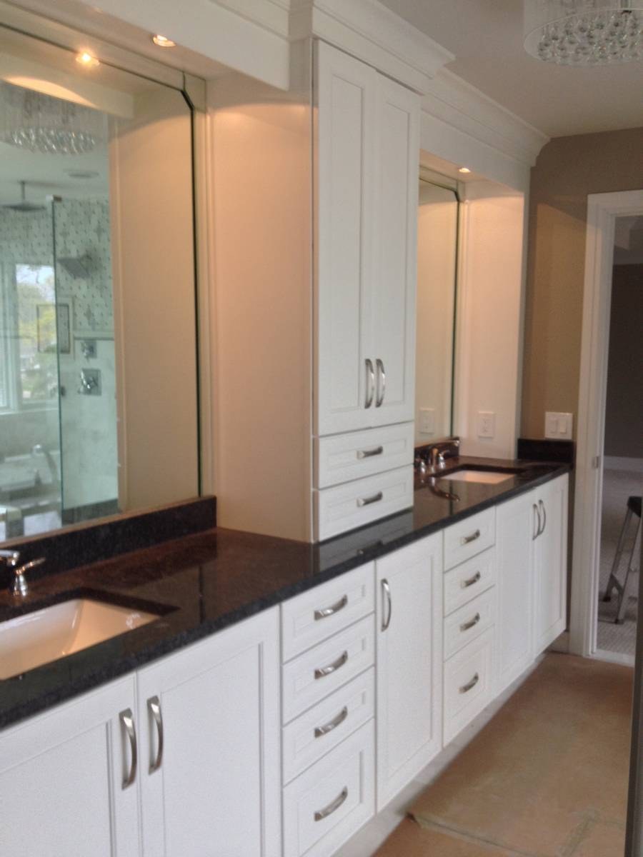 Primary bathroom remodel with white dual vanity, black granite tops, and center linen tower