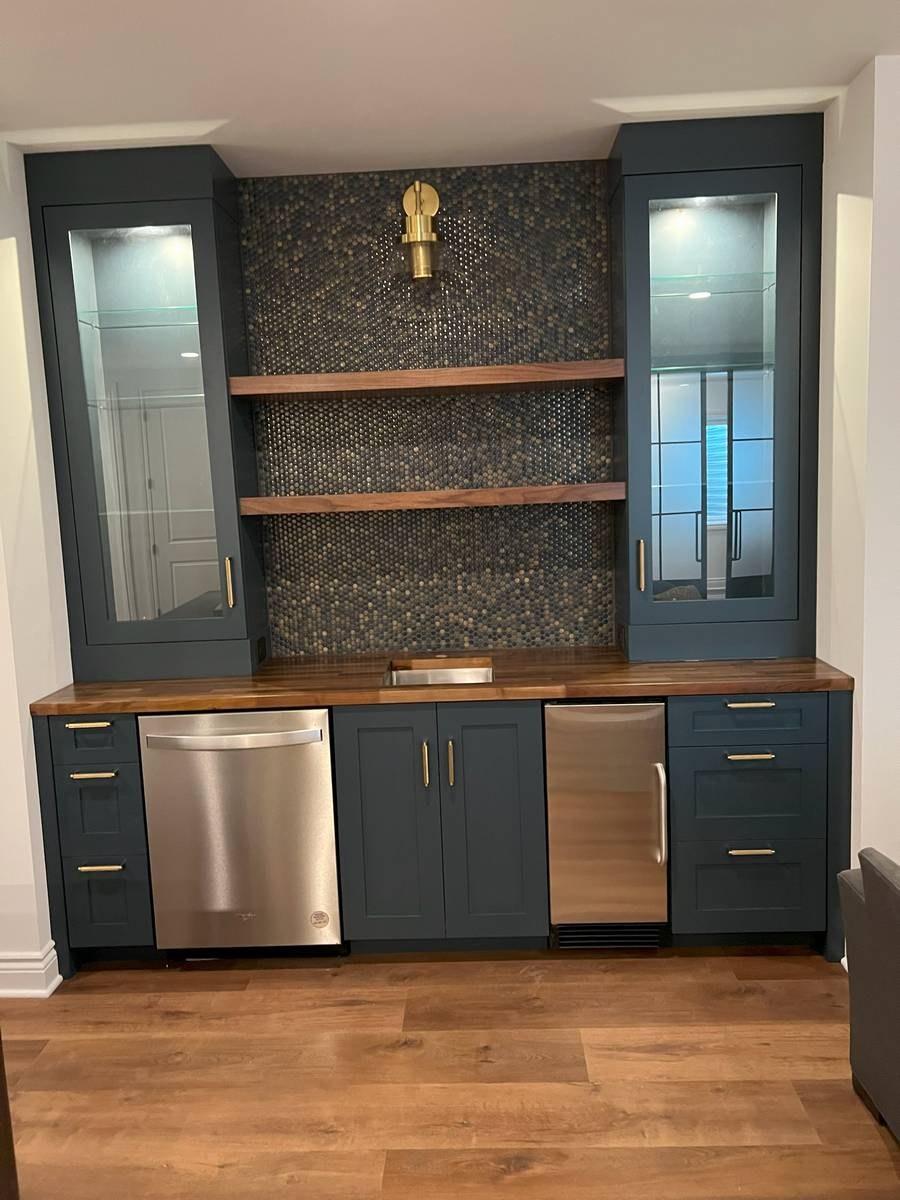 Basement wet bar with navy cabinetry and penny-round mosaic backsplash