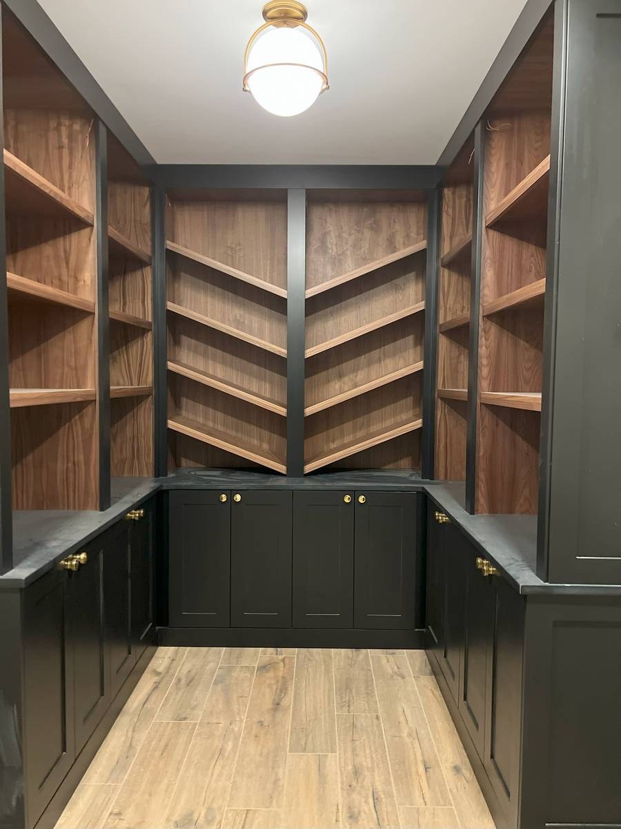 Custom walk-in butler's pantry addition with black shaker cabinets, walnut shelving, and brass hardware