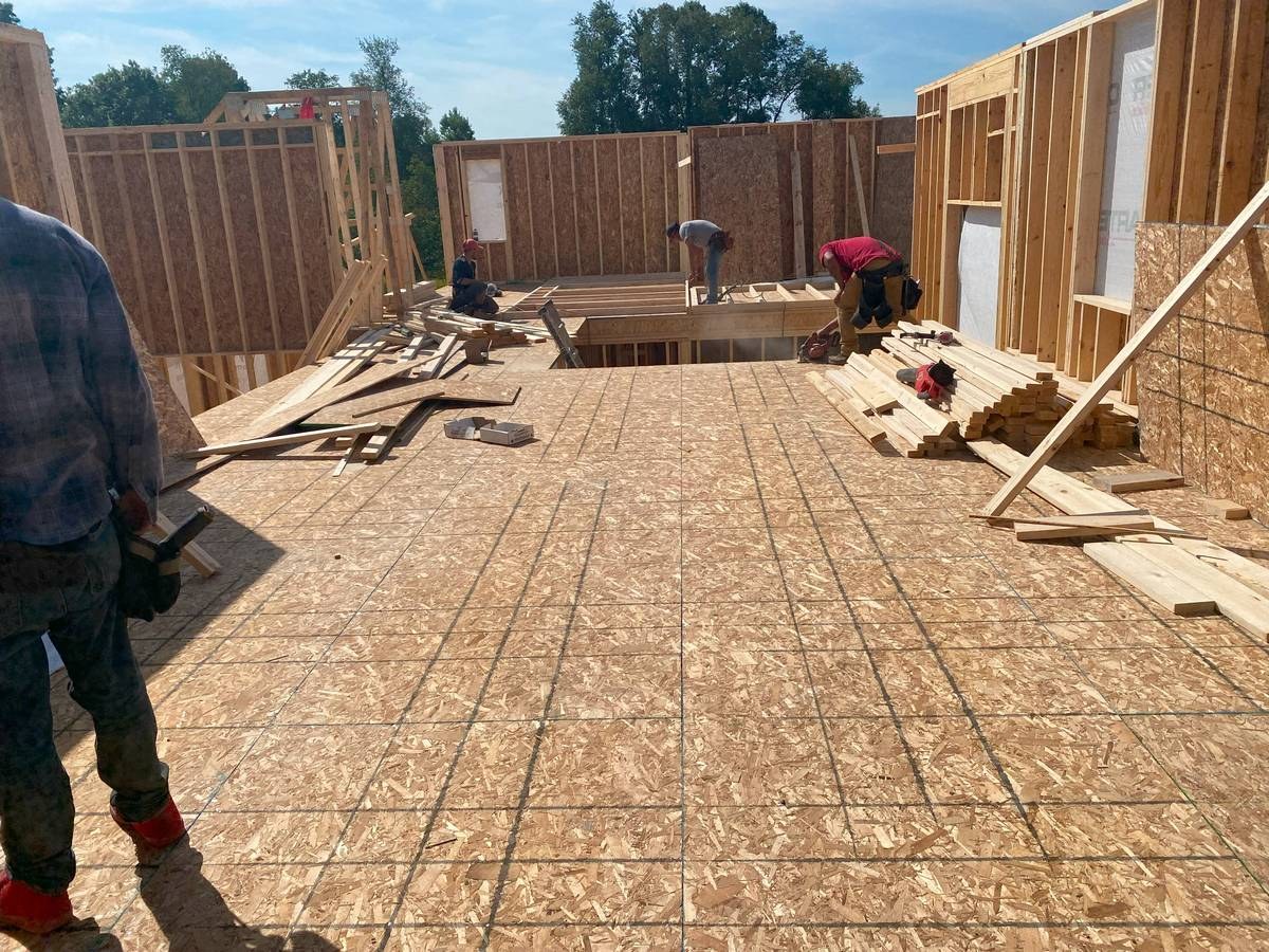 Construction crew framing walls and floor system on a custom new home build